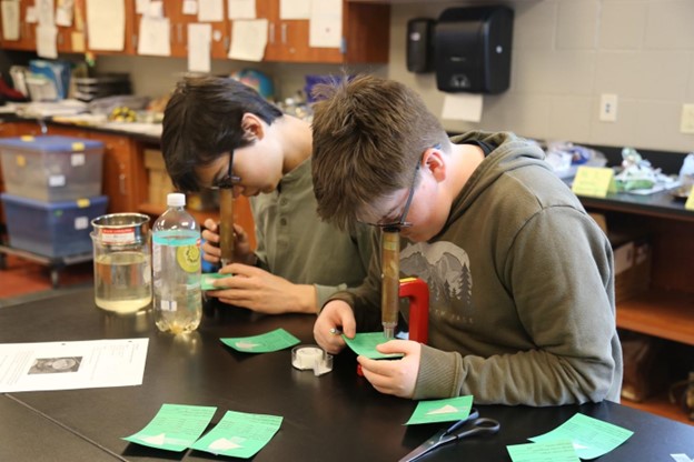Photo featuring two students using microscopes to complete a hands-on science activity